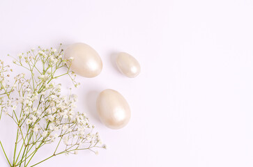 Mother-of-pearl Easter eggs and hepsophila flowers on a white background.