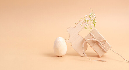 Easter eggs with a wooden bunny with a gift box and gepsophila flowers on a beige background