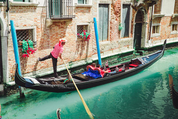 Italy, Venice - May 25, 2019: people at gondola taking tour by canal - obrazy, fototapety, plakaty