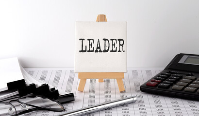 text LEADER on easel with office tools and paper.Top view. Business concept