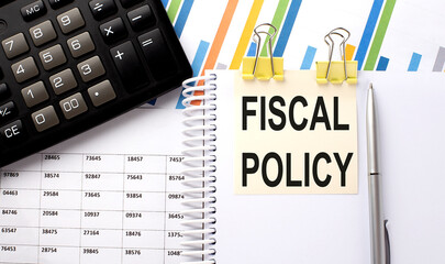 FISCAL POLICY text, written on a sticker with calculator,pen on chart background.