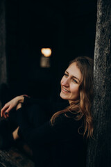 beautiful Ukrainian girl in black clothes near the old wooden house. The war in Ukraine. Portrait of a woman on a dark wooden background. Old abandoned wooden house. Old wooden window frame