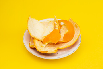 fresh orange mandarin peel on white dish on yellow