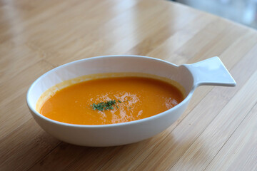 A thick pumpkin soup is served in an oval bowl.
