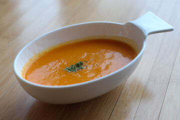 A thick pumpkin soup is served in an oval bowl.