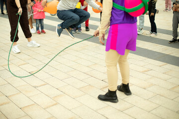 Children jump over a rope. Children's holiday with an animator. Competition for preschoolers on the square.