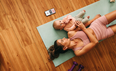 High angle view of a mom lying on an exercise mat with her baby