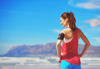She loves working out on the beach. Rearview shot of a young woman standing with her hands on her hips on the beach.