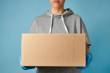 Delivery man holding cardboard box on blue background