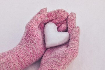 Winter love concept. Heart of snow in the hands of a woman.