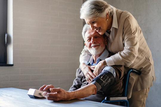 Happy Senior Couple Measuring Blood Pressure At Home