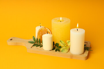 Concept of relaxation with aroma candles on orange background