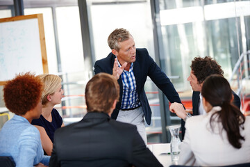 Distributing tasks to the team. Cropped shot of a group of business professionals in an office...