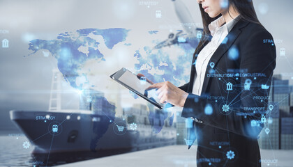 Attractive european businesswoman using tablet with abstract glowing blurry global delivery scheme hologram on transport dock background. Logistics and network concept. Double exposure.