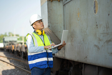 The engineer in a helmet and uniform,Working with tablet for plan,Engineers working on railway train statation.