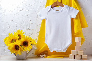 White baby short sleeve bodysuit mockup with sunflowers and wooden toys