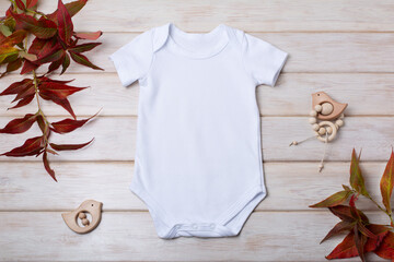 White baby short sleeve bodysuit mockup with red grass and baby toys