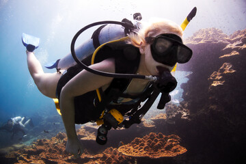 Ocean adventurer. Female scuba diver closely passes over a coral reef.