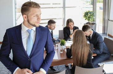 Young businessman standing in office with his collegue on the background