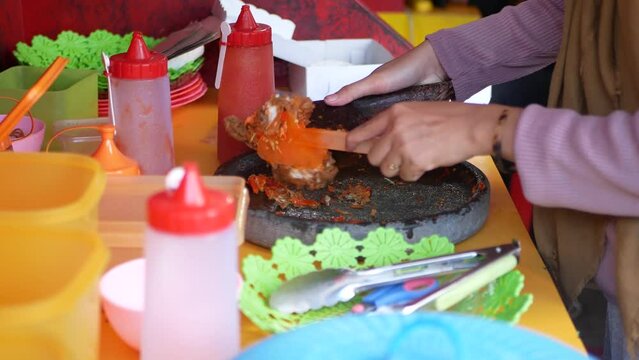 Making ayam geprek, popular fusion dish of smashed southern fried chicken with topping of red chili relish. Ayam geprek is one of the favorite foods among young people of Indonesia.