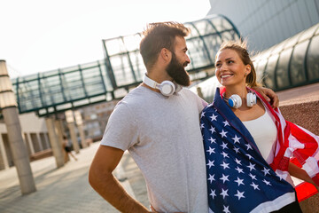 Portrait of young happy fitness couple exercising and having fun together outside with USA flag.