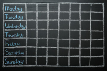 Weekly school timetable drawn on black chalkboard