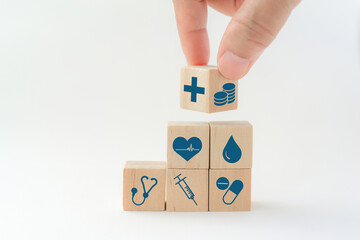 senior's hand flip wood cube with icon healthcare medical and coin on wood background, copy space for reduce medical expenses, health insurance concept