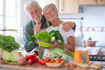 Fototapeta Attractive senior couple preparing vegetables together in the home kitchen. Caucasian elderly people enjoying healthy eating obraz