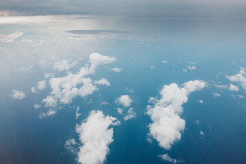 View of the earth from above through the clouds against the blue sky - the window of a flying plane