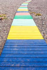 A beach path made of bright colored boards on pebbles on the seashore and on the beach - a resort...
