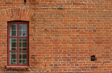 Brick wall with a window in an old building, can be used as a backdrop or background, copy space.