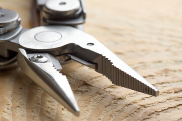 Accessories for electricians on the workshop table. Pliers elongated shape close up. Used for bending, cutting, clamping in electrical work. Construction and repair. Wooden background.