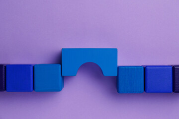 Bridge made of colorful blocks on violet background, flat lay. Connection, relationships and deal concept