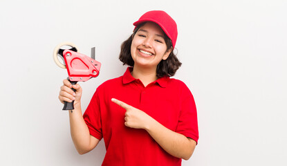 pretty hispanic girl smiling cheerfully, feeling happy and pointing to the side. packer concept