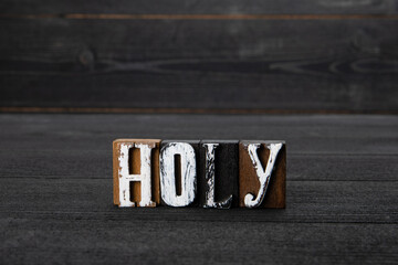 Holy. Text from blocks on a wooden texture background