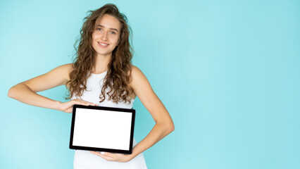 Digital promotion. Happy woman. Internet technology. Pretty smiling lady showing tablet computer with blank screen in hands isolated blue copy space.