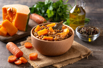 Lentil stew ragout with pumpkin and carrot in bowl on wooden table