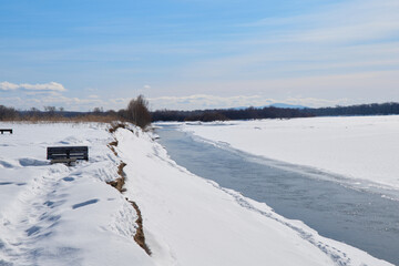 The mountain Russian river Khor in winter. Snow on the shore. A rapid flow of icy water.