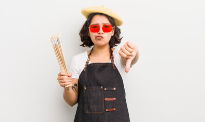 pretty hispanic girl feeling cross,showing thumbs down. art student concept