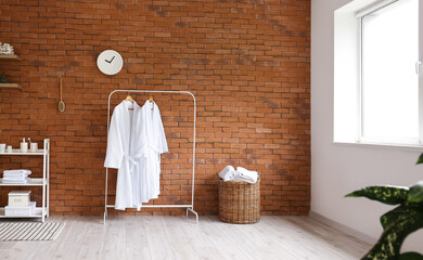 Interior of bathroom with shelving unit and rack with bathrobes