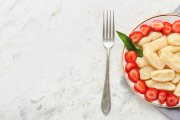 Plate of tasty lazy dumplings with strawberry and fork on light background, closeup