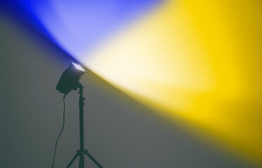 The lamp lights the white wall in color of Ukrainian flag in the dark room