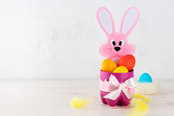 Craft hare with painted Easter eggs on a wooden table. Horizontal orientation, copy space.