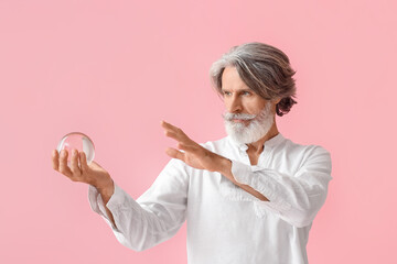 Mature man with crystal ball on color background