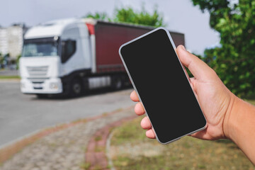 Phone in a man's hand. Against the backdrop of a truck. Logistics concept.