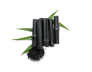 Composition with black bamboo sticks, activated carbon powder and leaves on white background