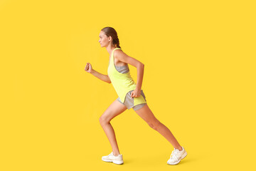 Fototapeta na wymiar Sporty young woman running on yellow background