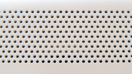 Background white plastic with round holes in the shape of a lattice, robot vacuum cleaner texture
