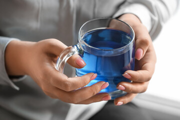 Woman with cup of tasty blue tea, closeup