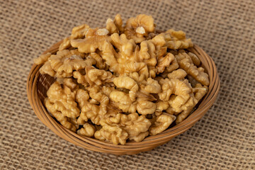 Peeled walnut in a basket on a burlap background.
